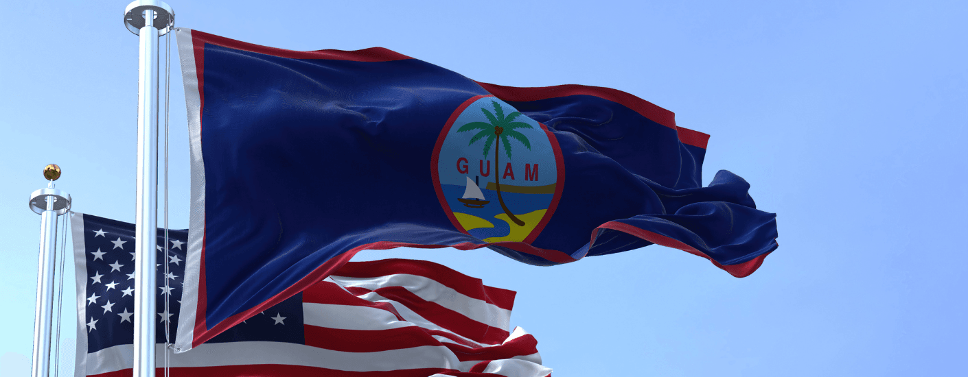 Guam and U.S. flags waving against a blue sky, accompanying a guide to VA home loans in Guam.