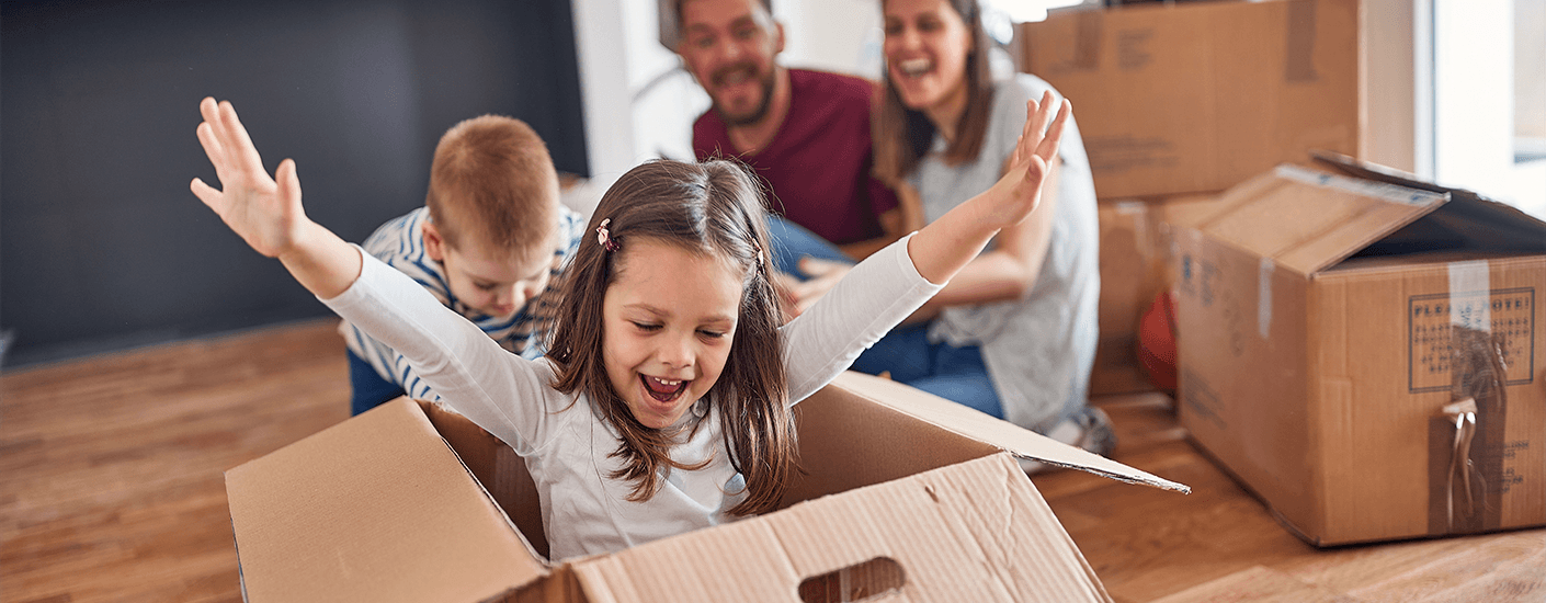 Happy family moving into a new home, with kids playing among moving boxes.
