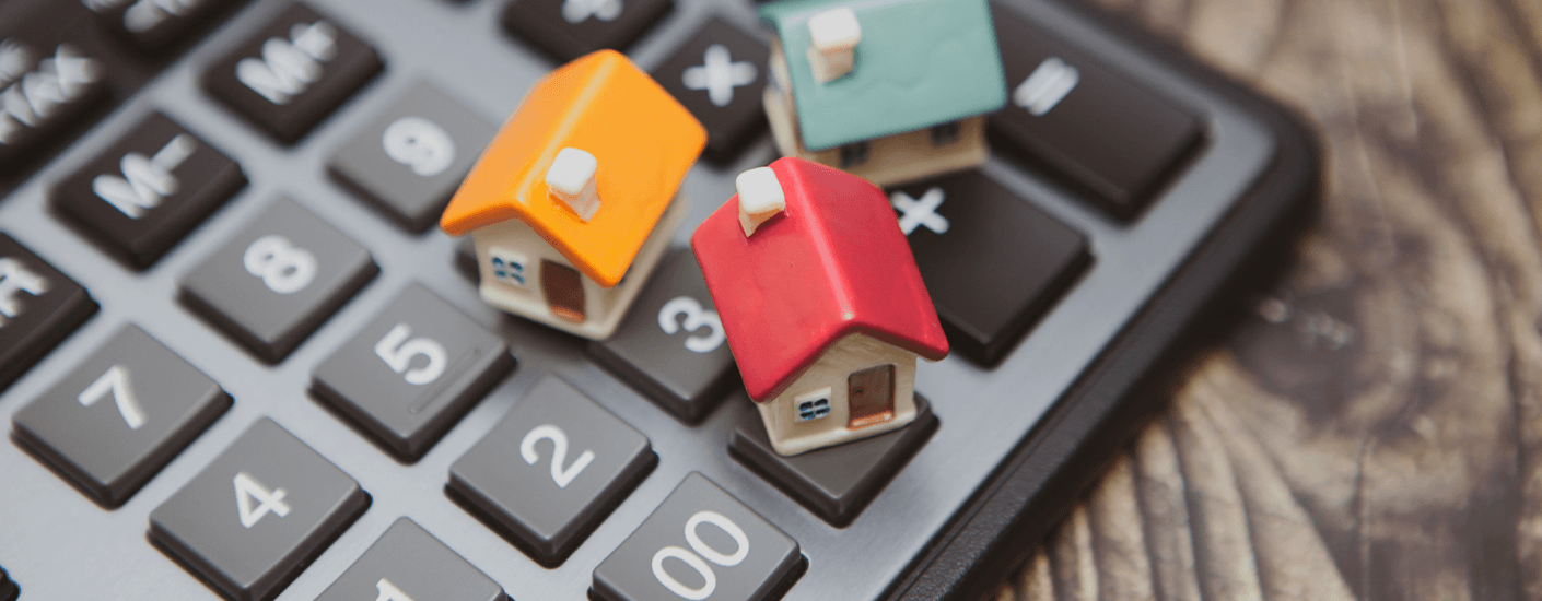 Small model houses on a calculator representing how mortgage payments are calculated.